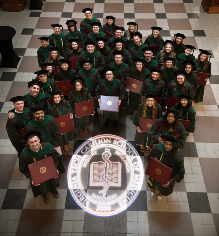 Students in the VTCSOM Class of 2024 gather around a projection of the school seal in the atrium of Roanoke's Jefferson Center.